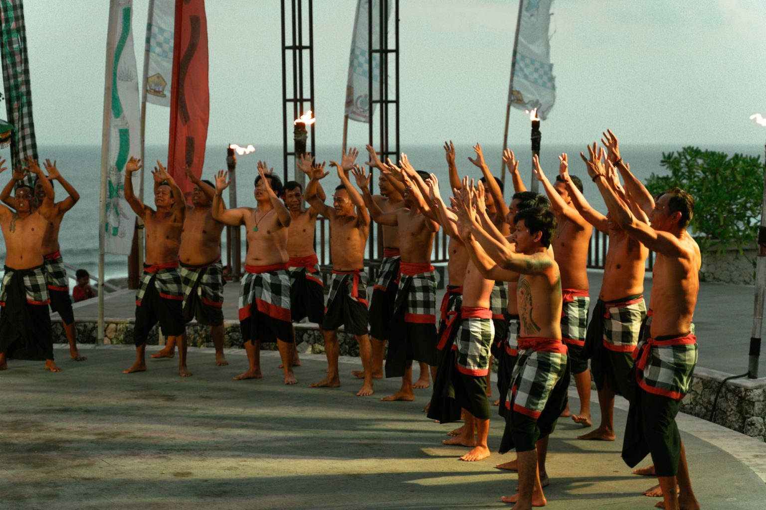 Kecak dance performed outdoors at sunset with the ocean behind
